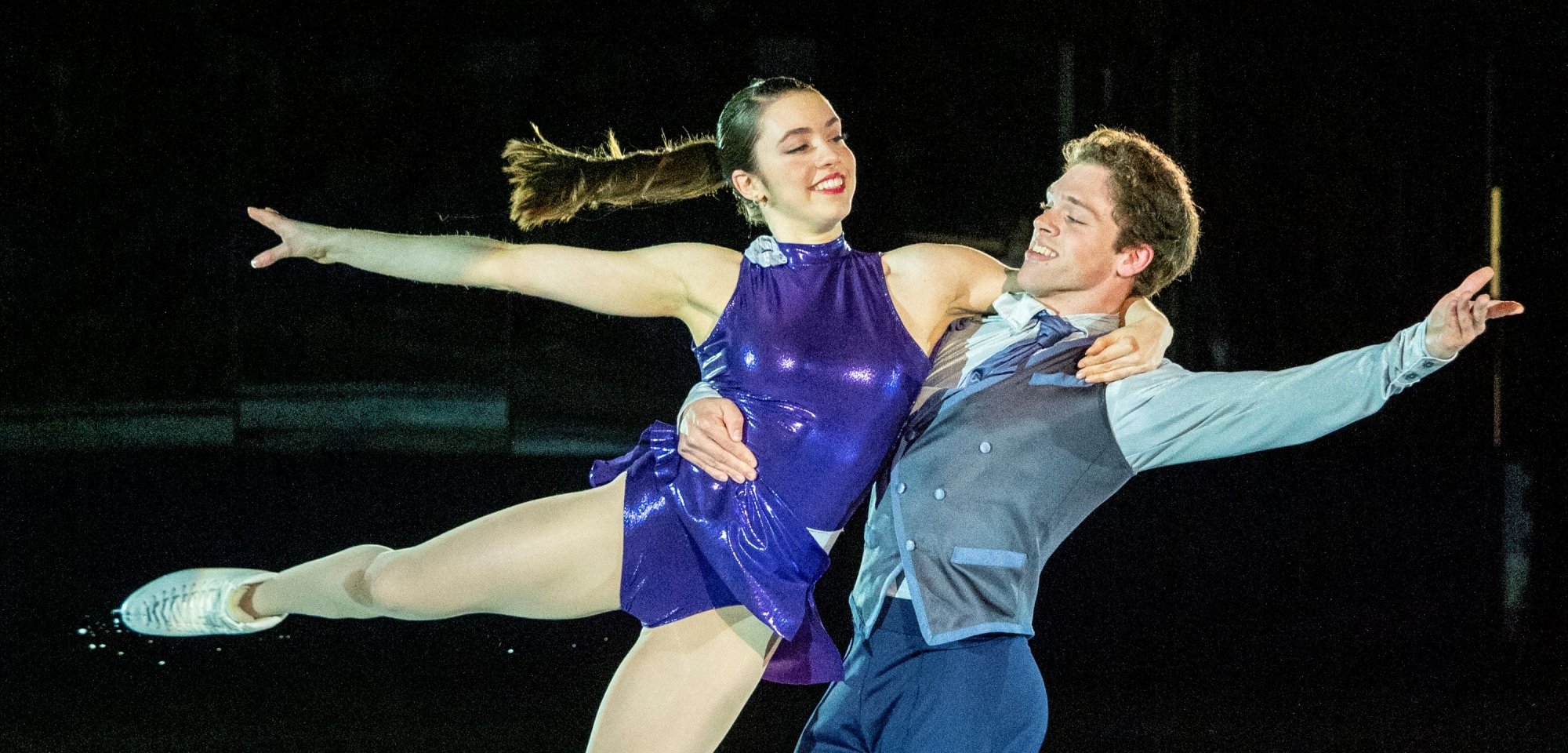 Two ice skaters performing at a skating rink