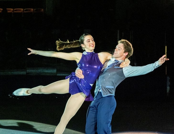 Two ice skaters performing at a skating rink