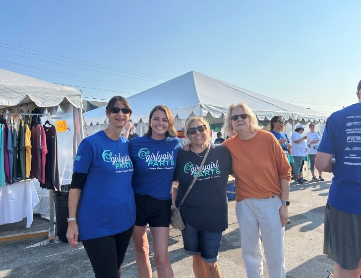 Four people in front of tents in an outdoor market