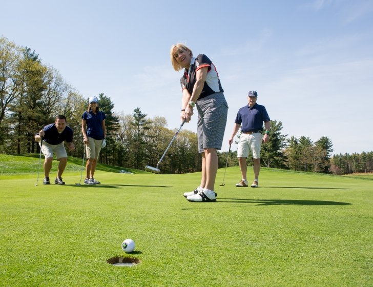 Four golfers playing a round on a course on a sunny day