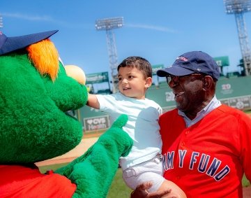 Two people interacting with Wally at Fenway Park