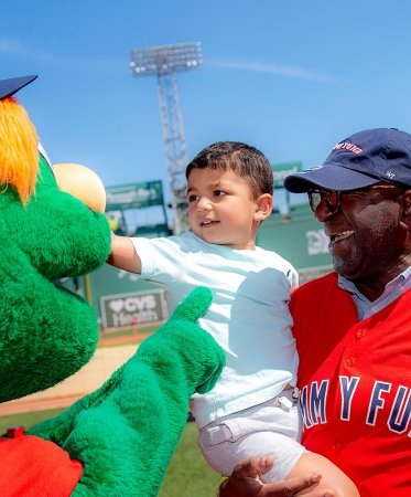 Two people interacting with Wally at Fenway Park