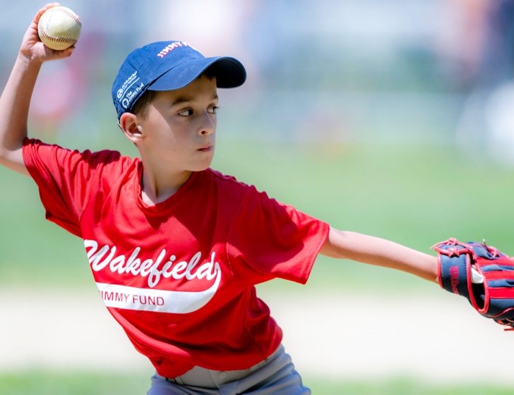 Little League player throwing a ball wearing Jimmy Fund gear