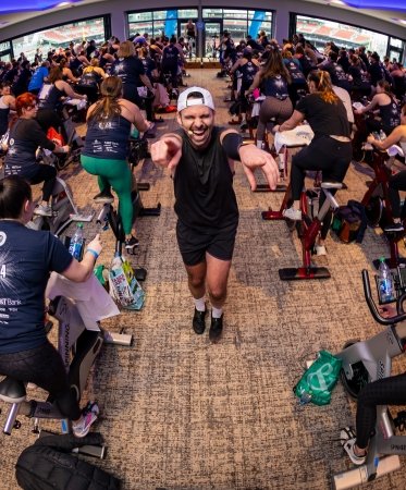 A spin instructor cheers on participants at the PMC Winter Cycle, an indoor spin event at Fenway Park 