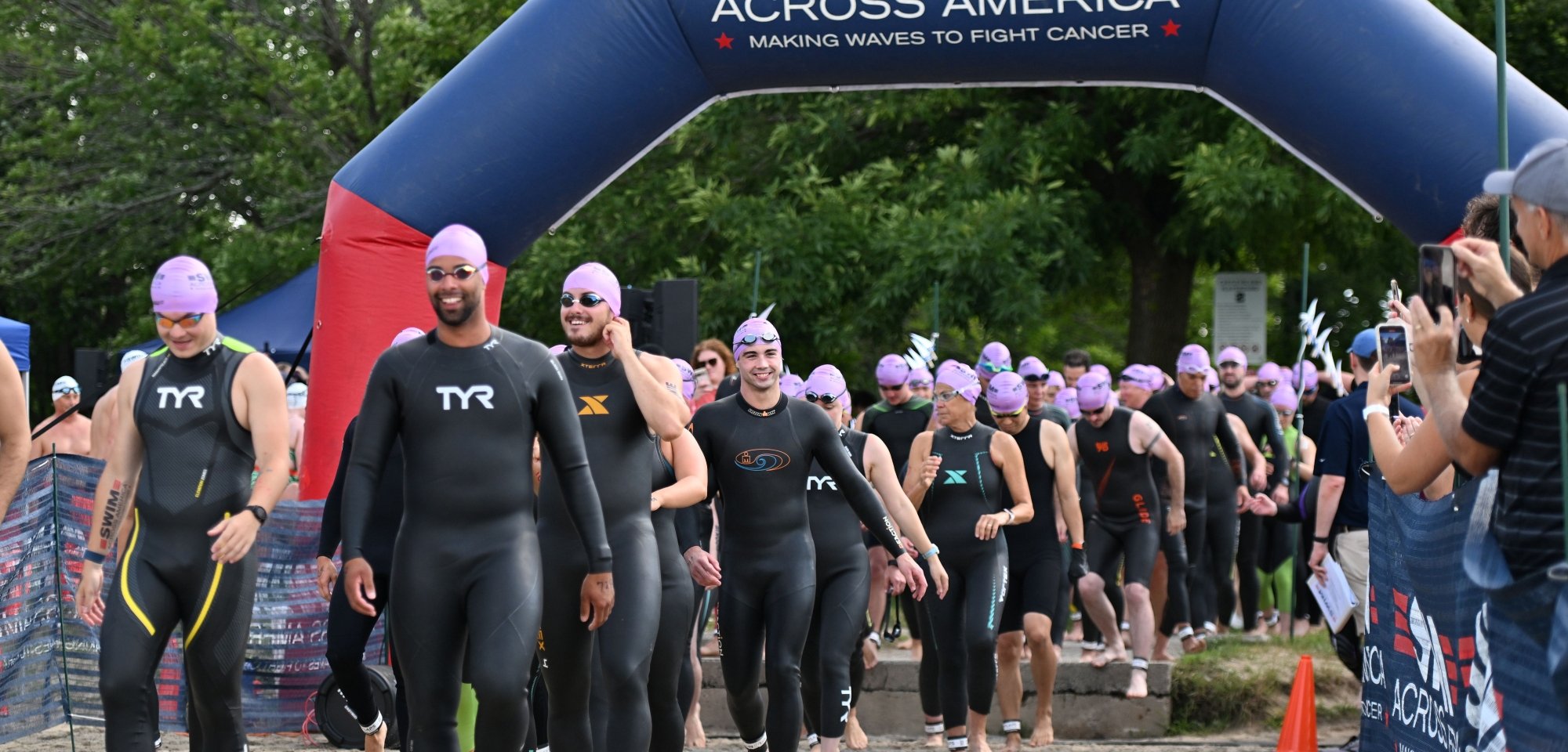 Swimmers in their gear at the starting line of a Swim Across America race