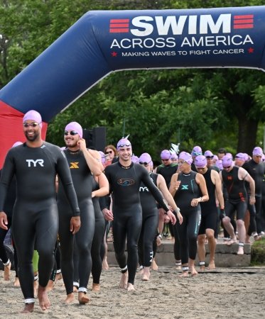 Swimmers in their gear at the starting line of a Swim Across America race