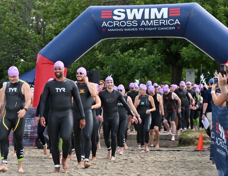 Swimmers in their gear at the starting line of a Swim Across America race