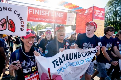 A Walk team celebrates as they cross the finish line holding their team sign