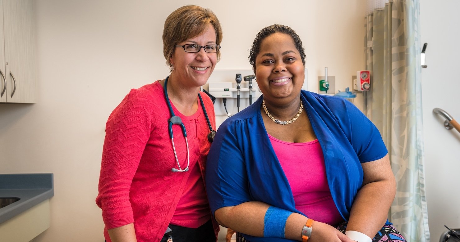 A provider and a patient sit in an exam room