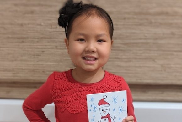 Young patient holding the snowman holiday card she designed