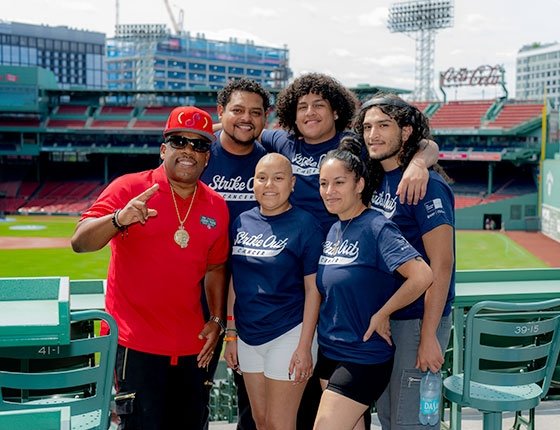 A group of people standing in Fenway Park wearing Strike Out Cancer shirts