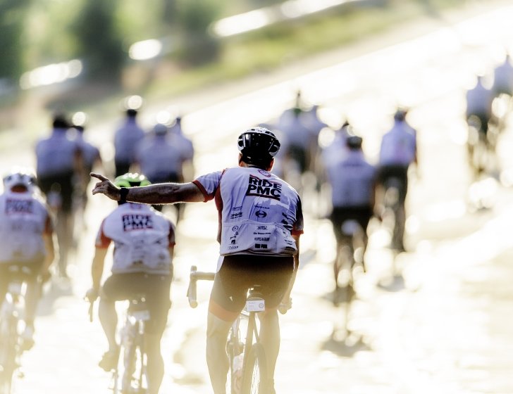Group of bike riders with their backs to the camera wearing 'Ride PMC' jerseys