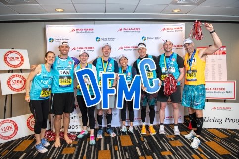 Group of runners stand together holding large 'DFMC' letters