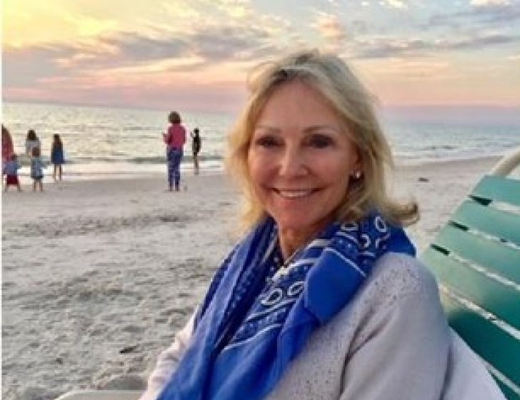 Dawn sitting on a chair on the beach with sunset in background