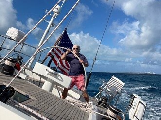 Michael at the helm of a boat with the ocean behind him
