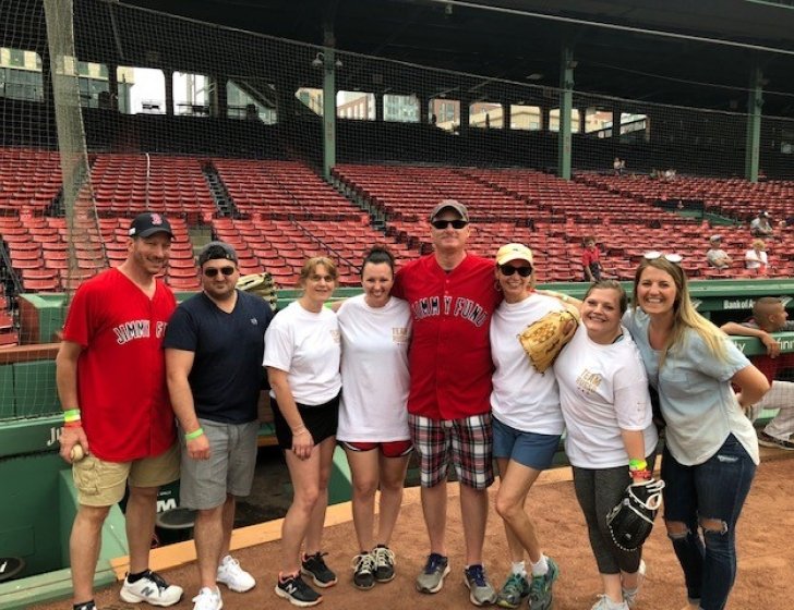Andy standing in front of the bleachers at Fenway Park with family and friends 