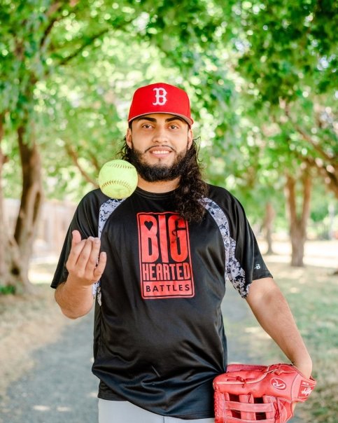 Person holds baseball glove and ball wearing Big Hearted Battles T-shirt