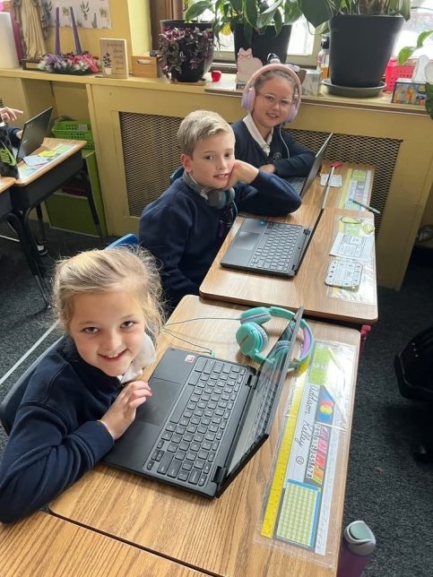 Three students at desks with laptops