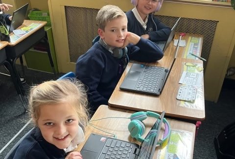 Three students at desks with laptops