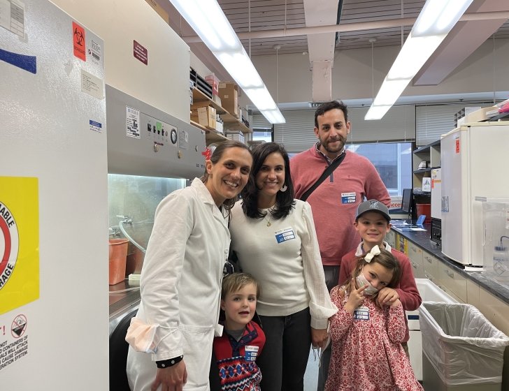 Patient and family smile together with Dr. Nina in a lab