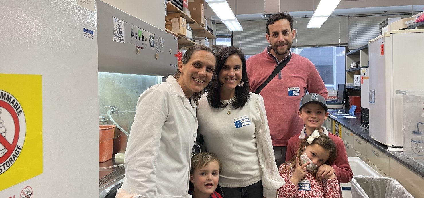 Patient and family smile together with Dr. Nina in a lab