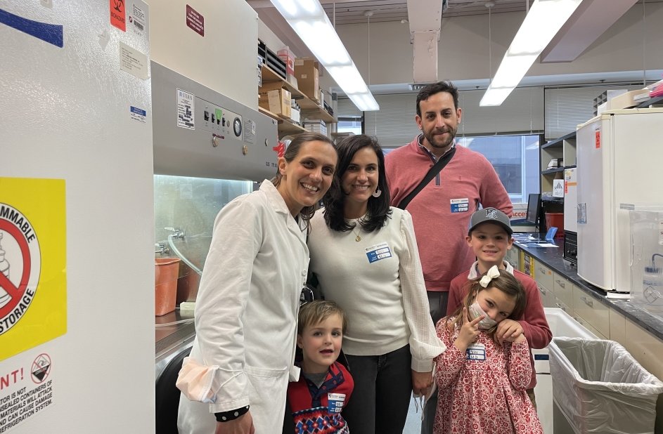 Patient and family smile together with Dr. Nina in a lab