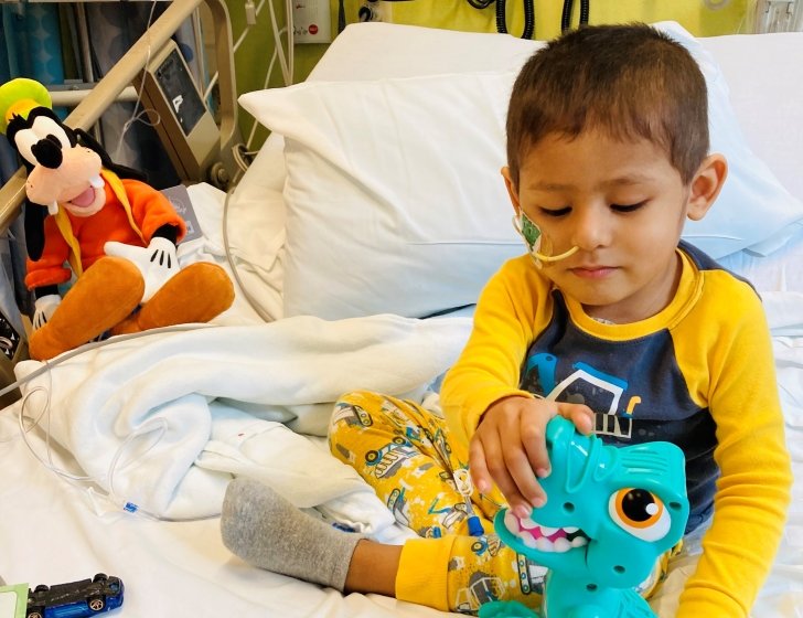 Cael in a hospital bed playing with toys