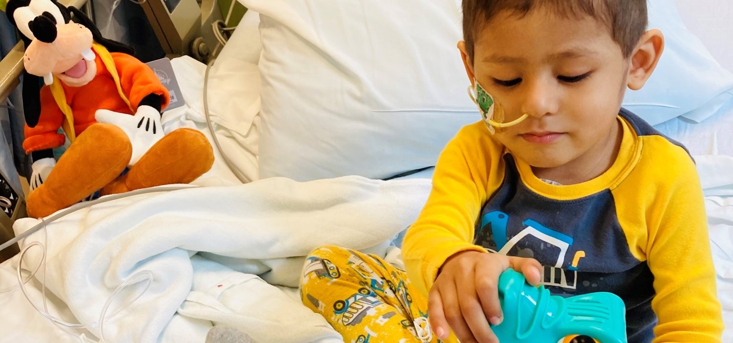 Cael in a hospital bed playing with toys