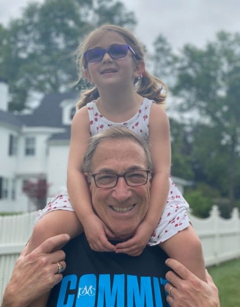 Granddaughter sits on grandfather’s shoulders