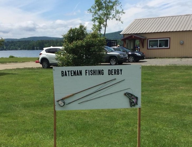 Sign reading 'Bateman Fishing Derby' with a lake and woods in the background