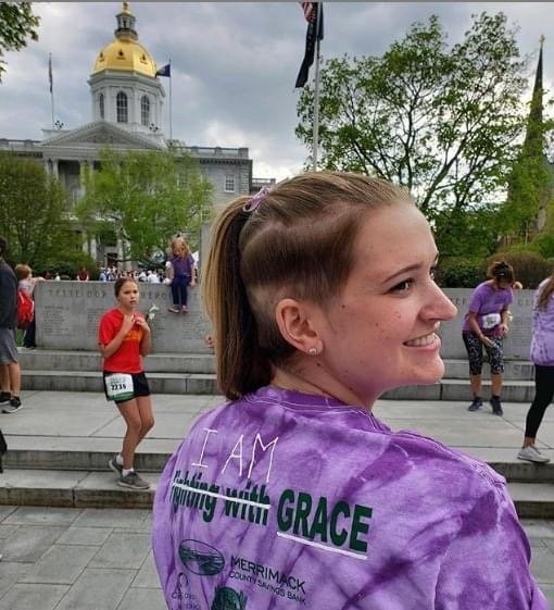 Grace with her back turned, showing her 'Fighting with Grace' T-shirt