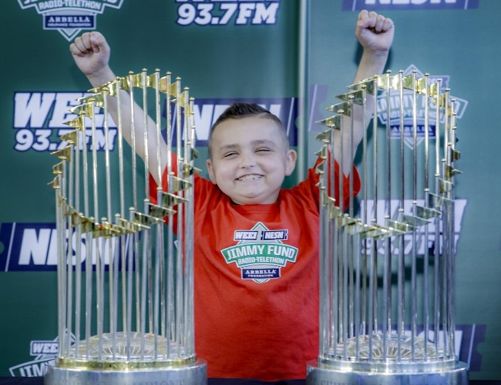 Grady stands with both arms in the air behind two championship trophies