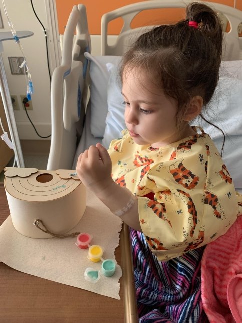 Sonnie painting a rainbow in a hospital bed