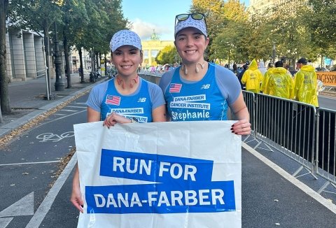 Kristina and Stephanie in their running gear holding a Run for Dana-Farber sign
