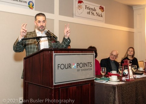 Brad speaking at a podium at a past Friends of St. Nick luncheon