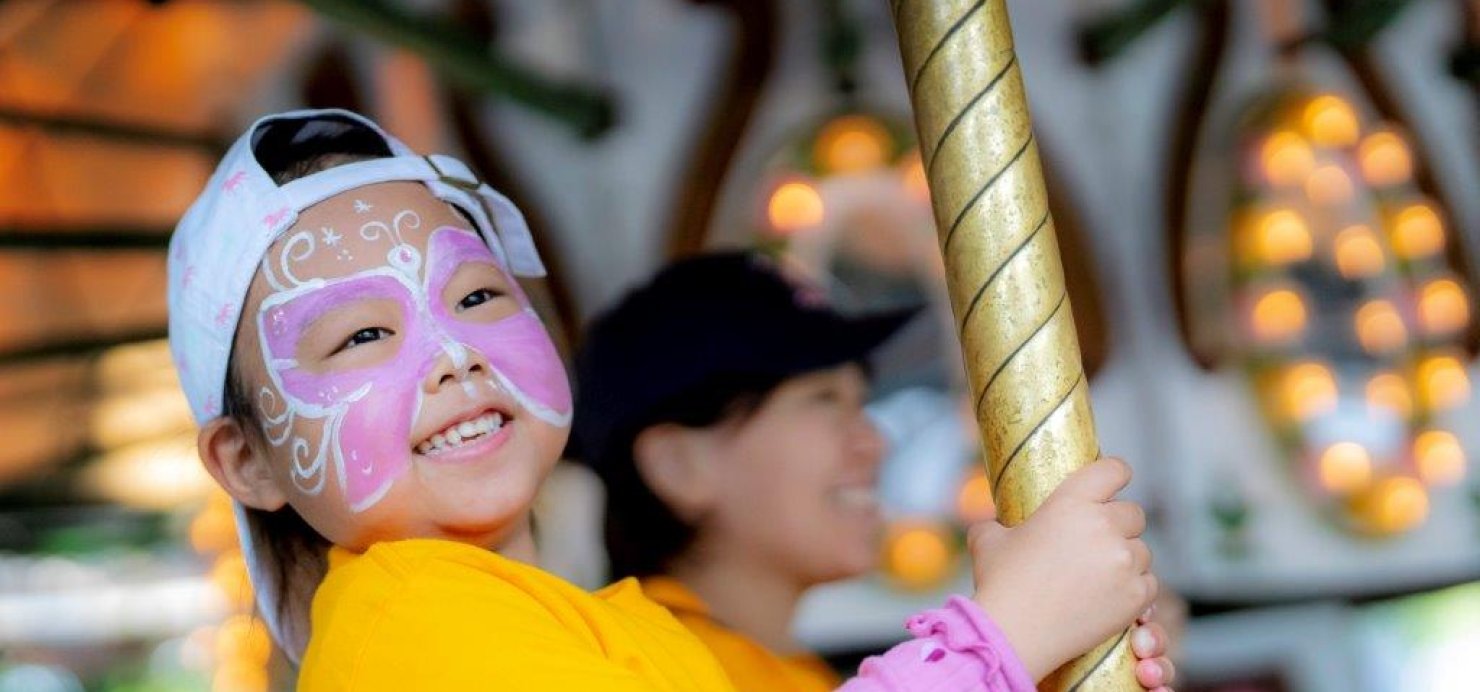 A child on a merry-go-round wearing butterfly face paint