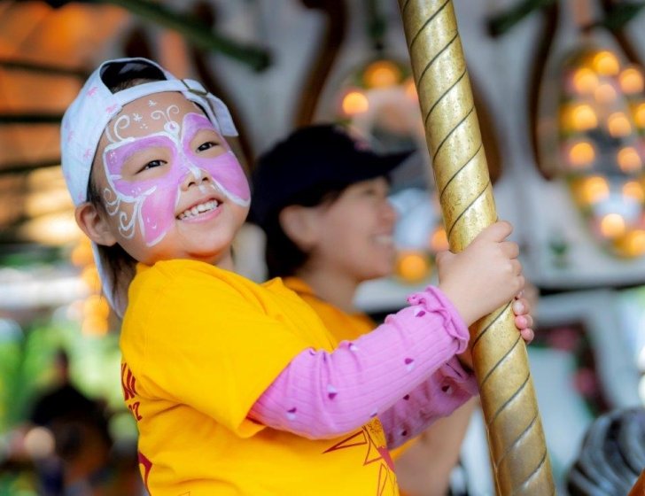 A child on a merry-go-round wearing butterfly face paint