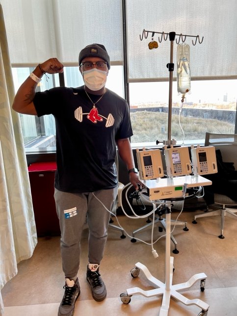Lamar stands with an IV drip, wearing a Red Sox shirt