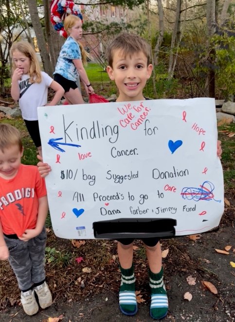 A child holding a Kindling for Cancer sign