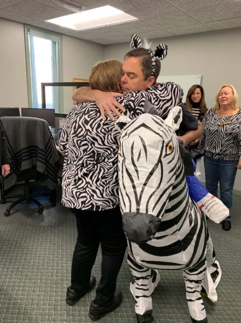 Cindy hugs her boss, both wear zebra outfits