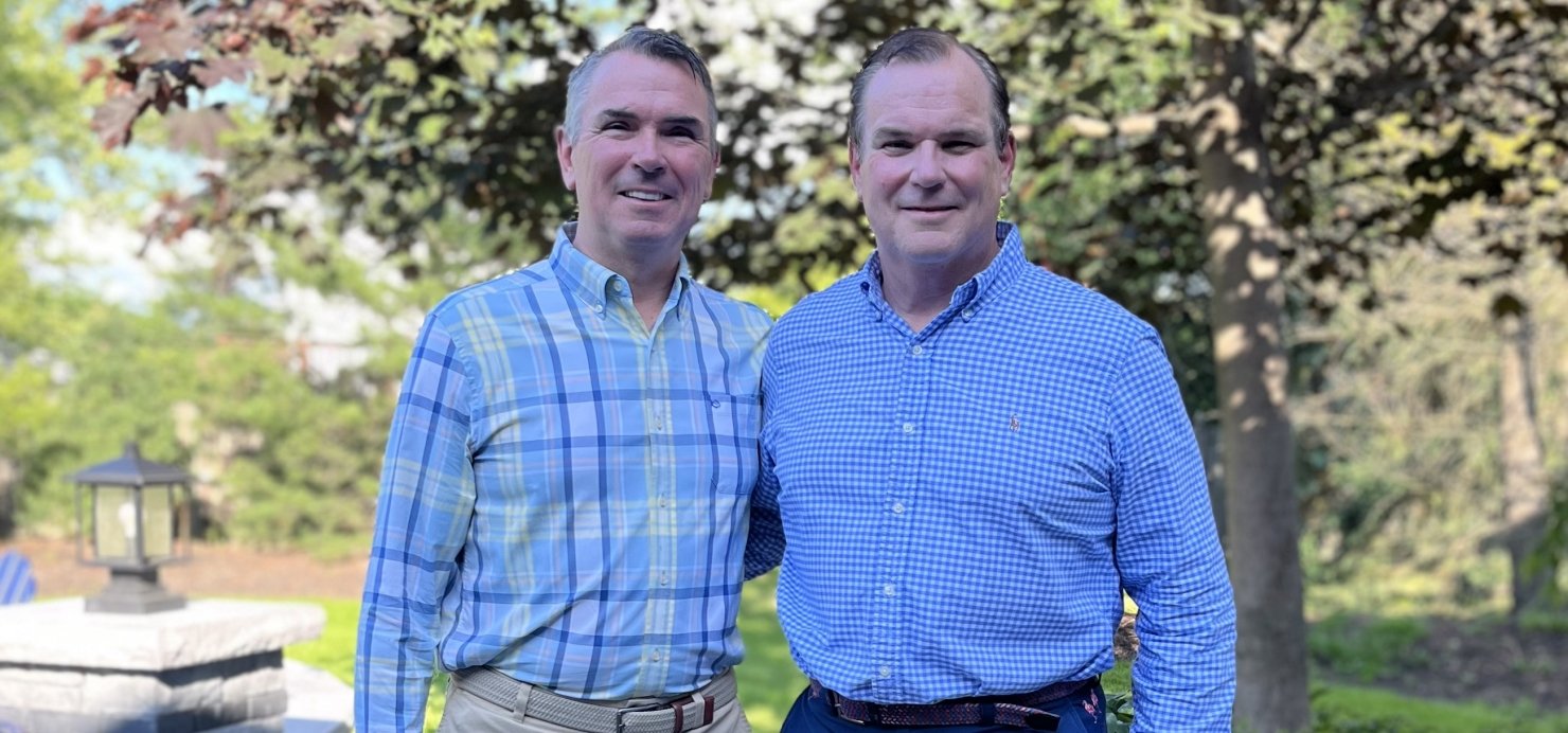 Bill and Matt stand together in front of a tree