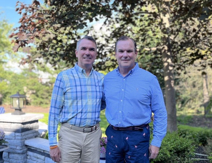Bill and Matt stand together in front of a tree