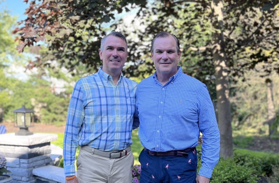 Bill and Matt stand together in front of a tree