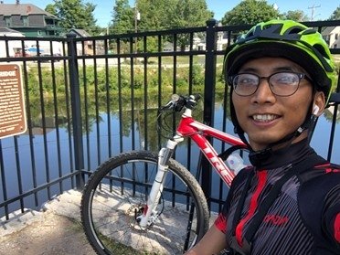 Benson stands in front of a river with his bike