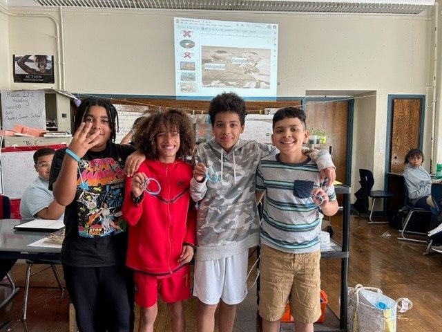 Four students holding blue Jimmy Fund bracelets