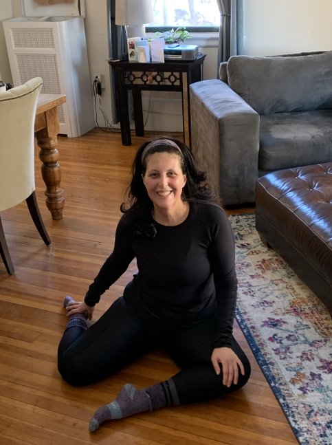 Marlene sits on living room floor stretching