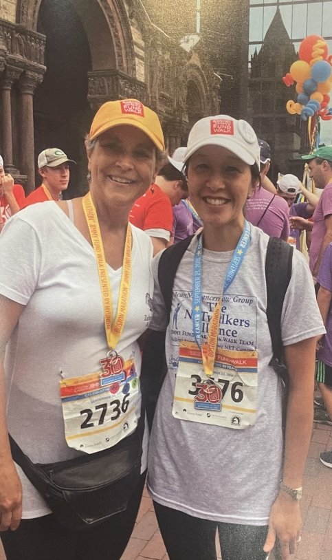 Two people wearing Jimmy Fund Walk hats, bibs, and medals