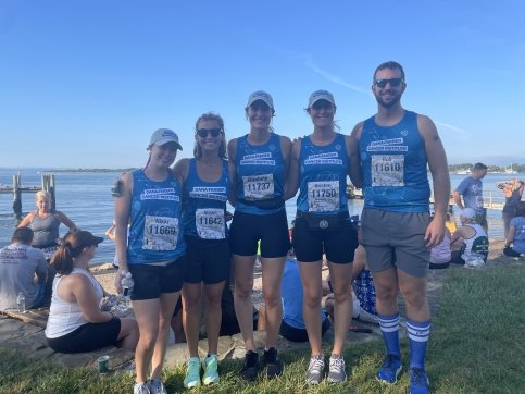 Elizabeth stands with four other runners on a field with the ocean in the background