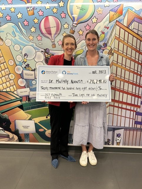 Elizabeth and Dr. Mullally holding a large check in front of The Imagine Display