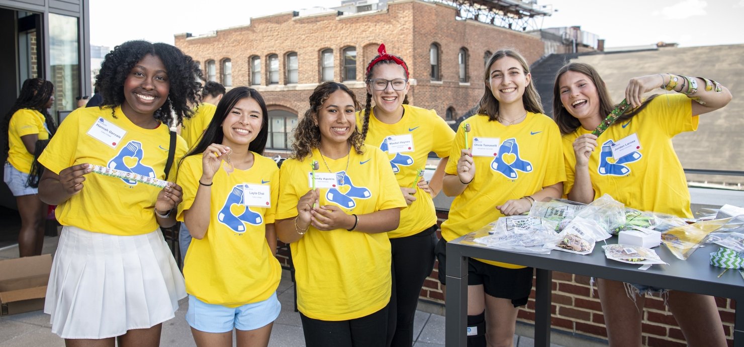 Group of scholars stand together on a roof deck wearing Red Sox T-shirts